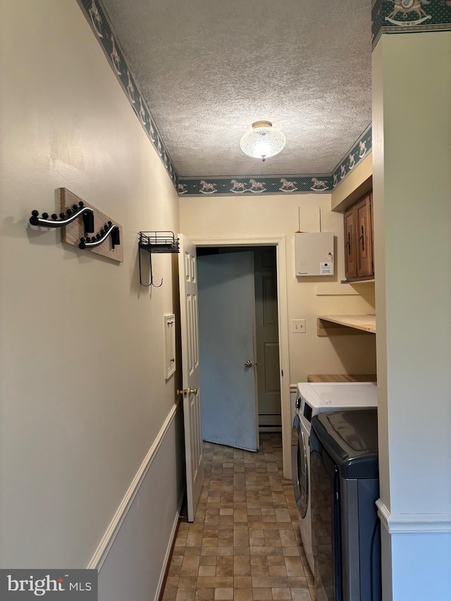 clothes washing area with cabinets, a textured ceiling, and washing machine and clothes dryer