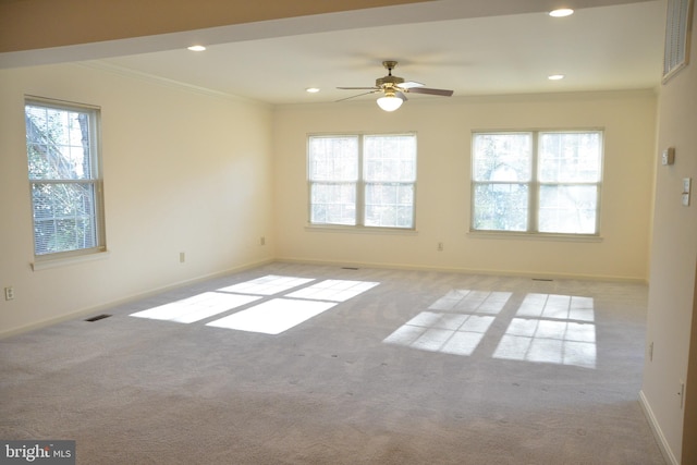 carpeted empty room featuring a wealth of natural light, crown molding, and ceiling fan