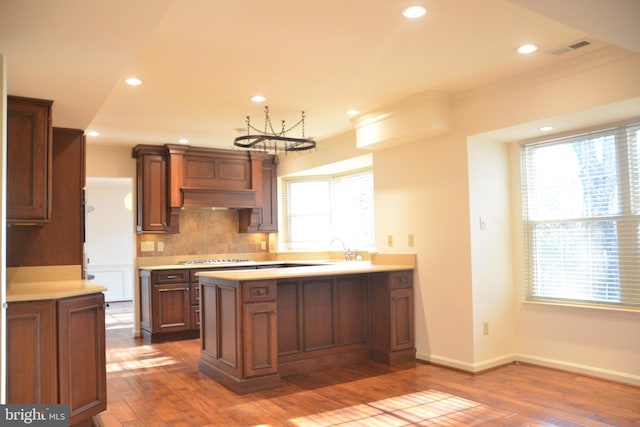 kitchen with dark hardwood / wood-style floors, a healthy amount of sunlight, crown molding, and tasteful backsplash