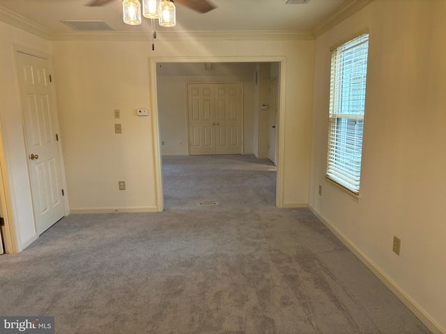 carpeted spare room with ceiling fan and crown molding