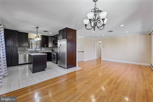 kitchen with decorative light fixtures, a center island, appliances with stainless steel finishes, and light hardwood / wood-style flooring