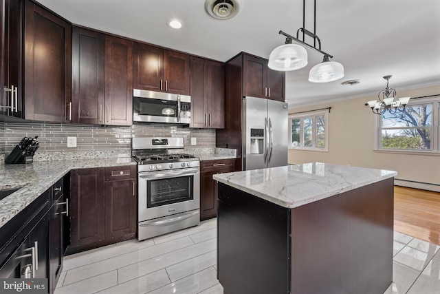 kitchen featuring appliances with stainless steel finishes, light wood-type flooring, light stone counters, a notable chandelier, and a center island