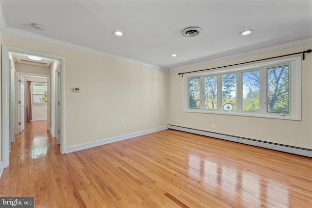 spare room with crown molding, light wood-type flooring, baseboard heating, and a wealth of natural light