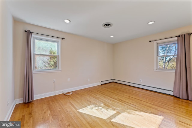 empty room featuring baseboard heating and hardwood / wood-style floors