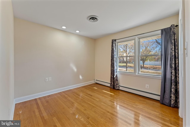 unfurnished room featuring light wood-type flooring and baseboard heating