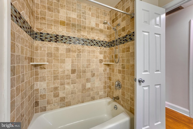 bathroom with hardwood / wood-style floors and tiled shower / bath combo