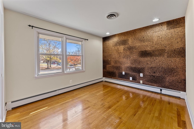 spare room with wood-type flooring and a baseboard radiator