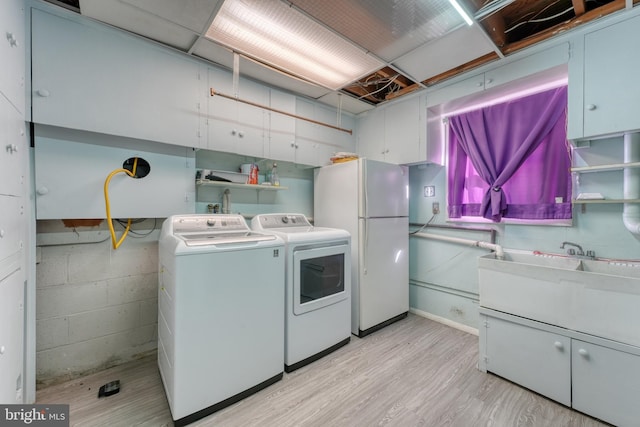 washroom featuring washing machine and dryer and light hardwood / wood-style flooring