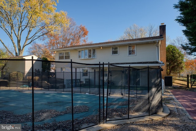 back of property featuring central AC unit and a covered pool