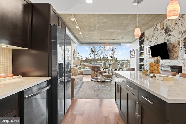 kitchen featuring dark brown cabinetry, decorative light fixtures, light stone counters, wood-type flooring, and stainless steel appliances