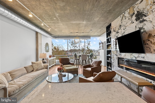 living room with floor to ceiling windows, rail lighting, a fireplace, wood-type flooring, and a chandelier