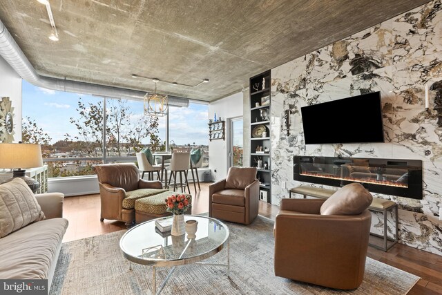 living room with hardwood / wood-style floors, floor to ceiling windows, a premium fireplace, and a chandelier