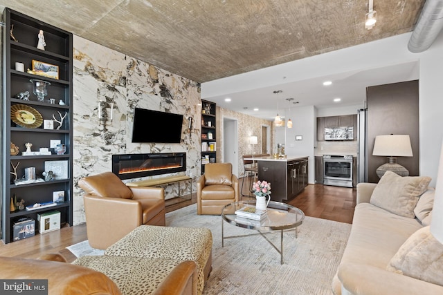 living room with a premium fireplace, hardwood / wood-style floors, and built in features