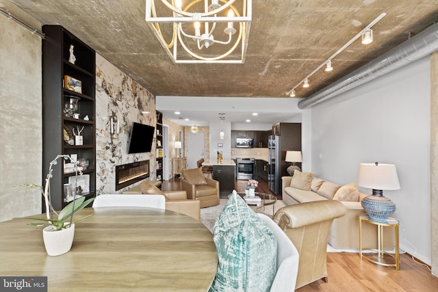 living room with a high end fireplace, light hardwood / wood-style floors, and a chandelier