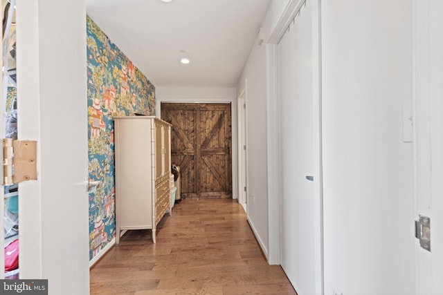 hallway featuring a barn door and light hardwood / wood-style flooring