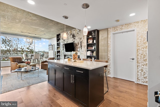 kitchen featuring a wealth of natural light, light hardwood / wood-style flooring, pendant lighting, and light stone counters