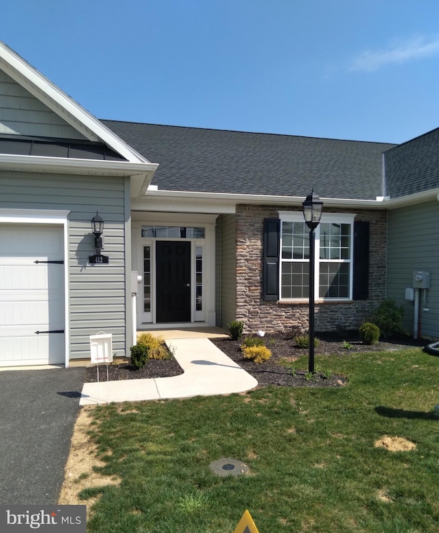 view of exterior entry featuring a yard and a garage