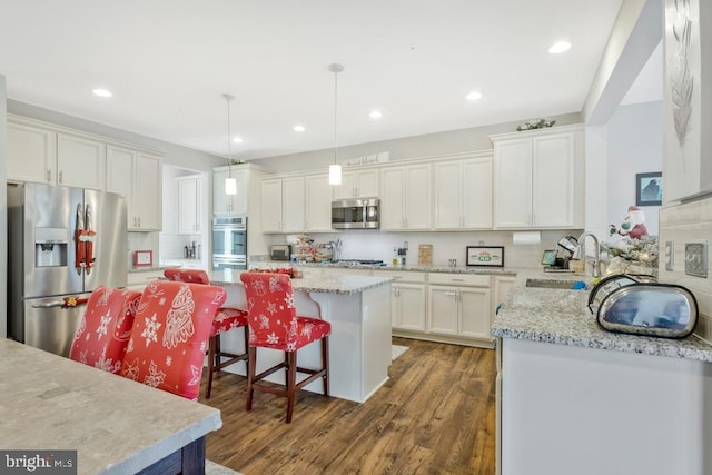 kitchen featuring white cabinetry, stainless steel appliances, a center island, and sink