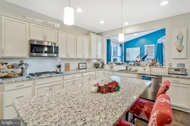 kitchen featuring a kitchen island, a breakfast bar, decorative light fixtures, sink, and stainless steel appliances