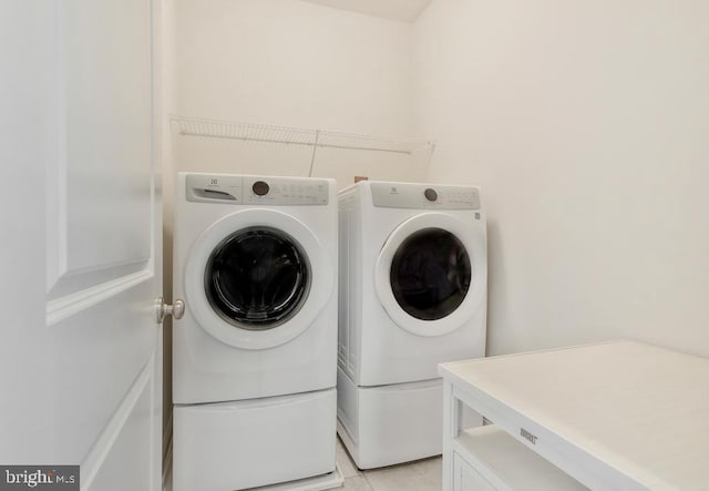 laundry area with separate washer and dryer and light tile patterned floors