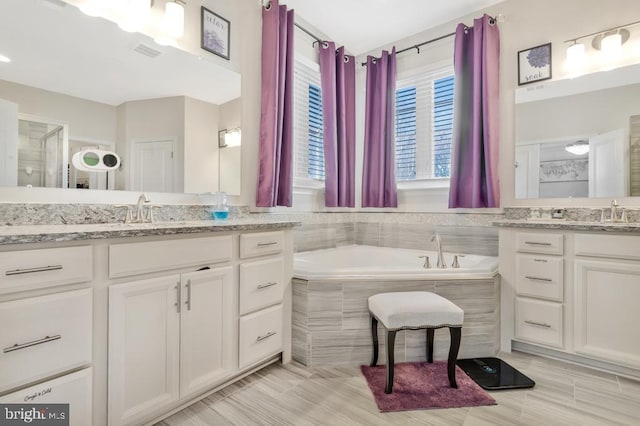 bathroom featuring vanity and tiled bath