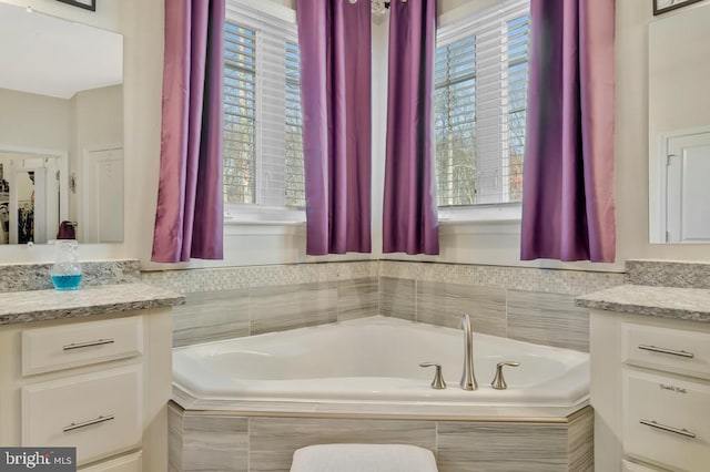 bathroom featuring vanity and tiled tub