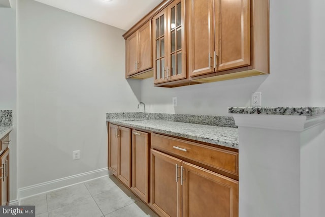 kitchen featuring sink, light tile patterned floors, and light stone counters