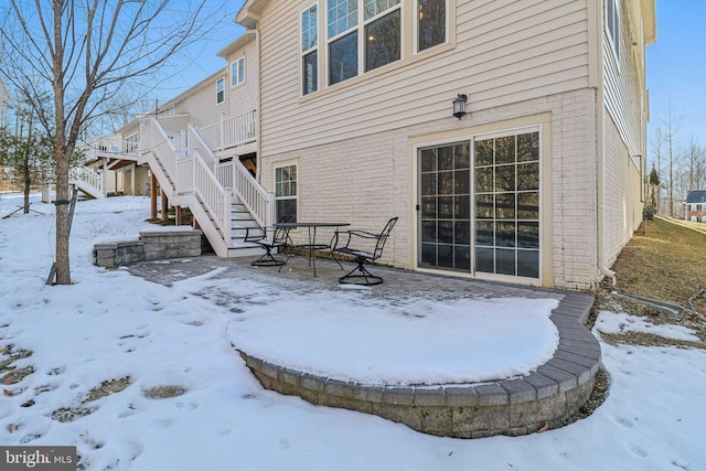 snow covered back of property with a deck