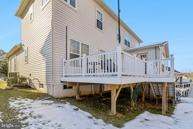 snow covered back of property featuring a deck