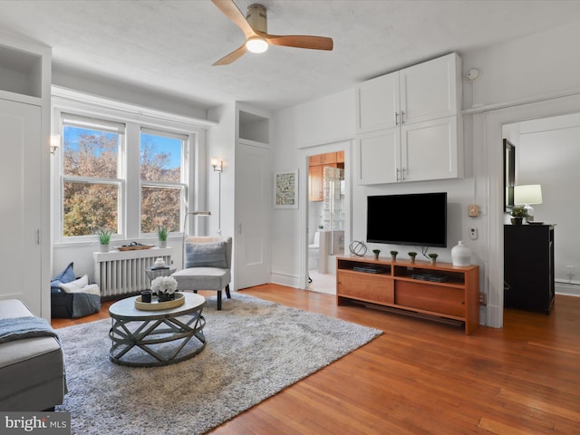 living room with radiator heating unit, hardwood / wood-style floors, and ceiling fan