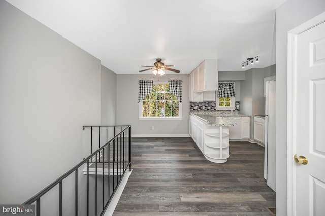 kitchen featuring ceiling fan, light stone countertops, dark hardwood / wood-style flooring, backsplash, and white cabinets