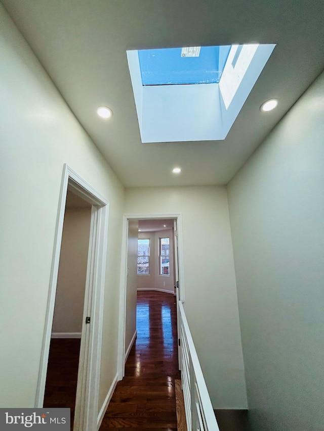 hallway featuring a skylight and dark hardwood / wood-style flooring