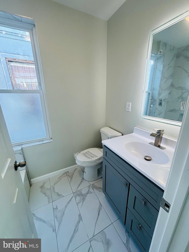 bathroom with tiled shower, vanity, and toilet