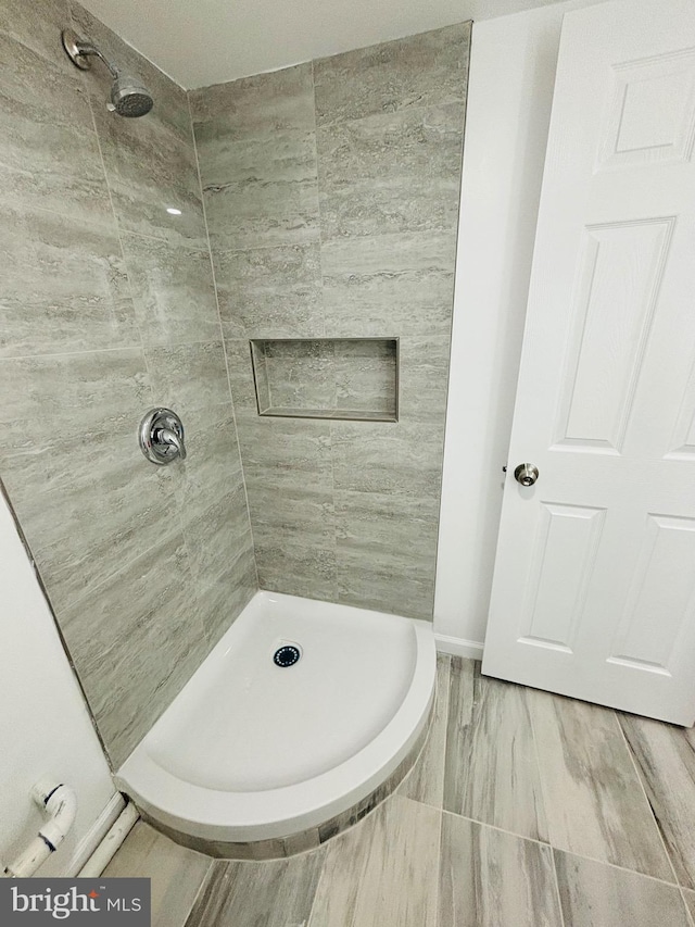 bathroom with a tile shower and hardwood / wood-style floors