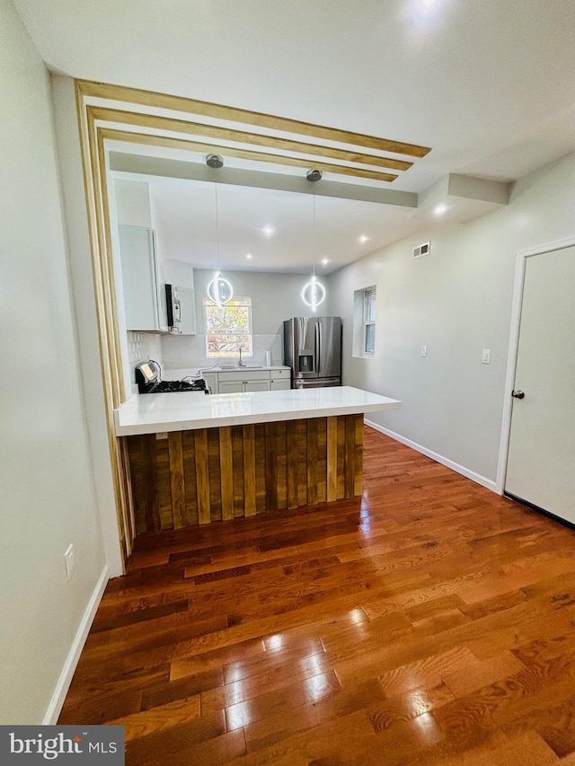 kitchen with dark wood-type flooring, white cabinets, sink, decorative light fixtures, and stainless steel appliances