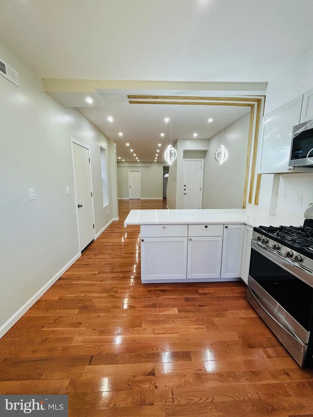 kitchen with white cabinetry, stainless steel appliances, light hardwood / wood-style flooring, kitchen peninsula, and pendant lighting