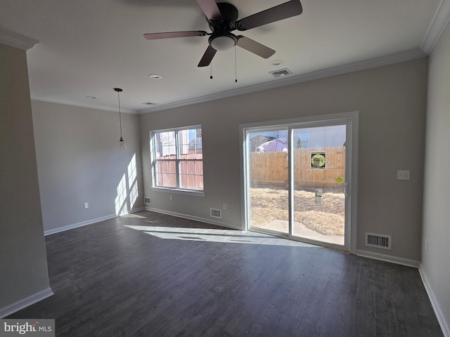 empty room featuring baseboards, visible vents, dark wood-style flooring, and crown molding