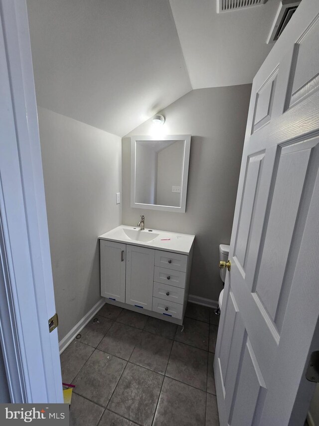 bathroom with baseboards, toilet, tile patterned flooring, vaulted ceiling, and vanity