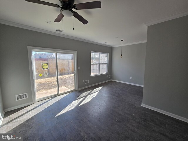 empty room featuring ornamental molding, visible vents, dark wood-type flooring, and baseboards