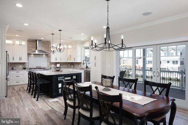 dining space featuring light wood-type flooring, an inviting chandelier, crown molding, and sink