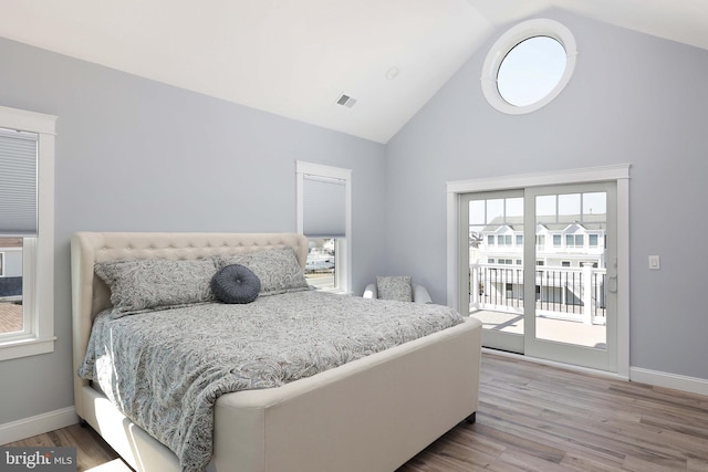 bedroom with access to outside, high vaulted ceiling, and light hardwood / wood-style floors