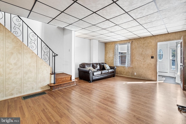 unfurnished living room featuring wood-type flooring, wooden walls, and a healthy amount of sunlight