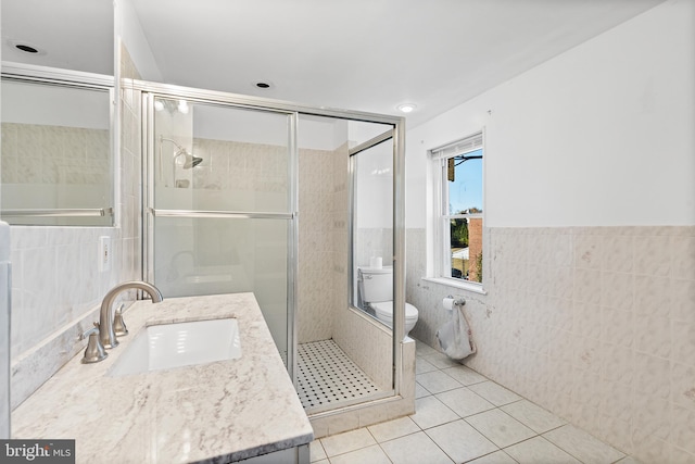 bathroom with vanity, tile patterned floors, toilet, tile walls, and an enclosed shower