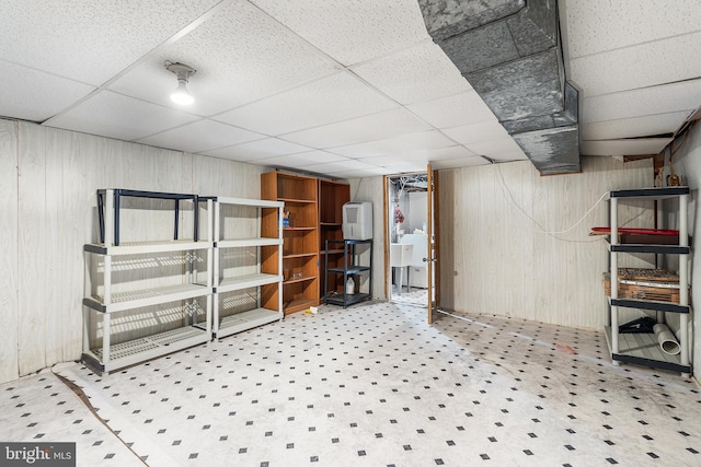 basement with a paneled ceiling and wooden walls