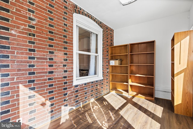 interior space featuring dark wood-type flooring and brick wall