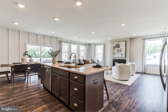 kitchen featuring a wealth of natural light, sink, dark wood-type flooring, stainless steel appliances, and a center island with sink