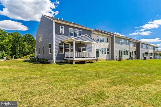 rear view of house featuring central AC unit, ceiling fan, and a yard