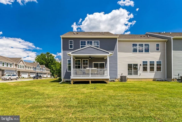 rear view of property with central AC unit, ceiling fan, and a yard