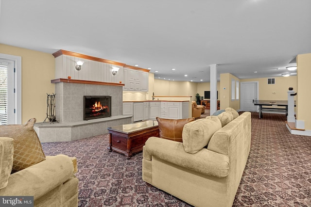 living room featuring a tiled fireplace, sink, and carpet floors