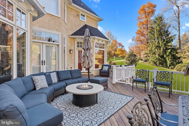 wooden deck with an outdoor living space with a fire pit and french doors